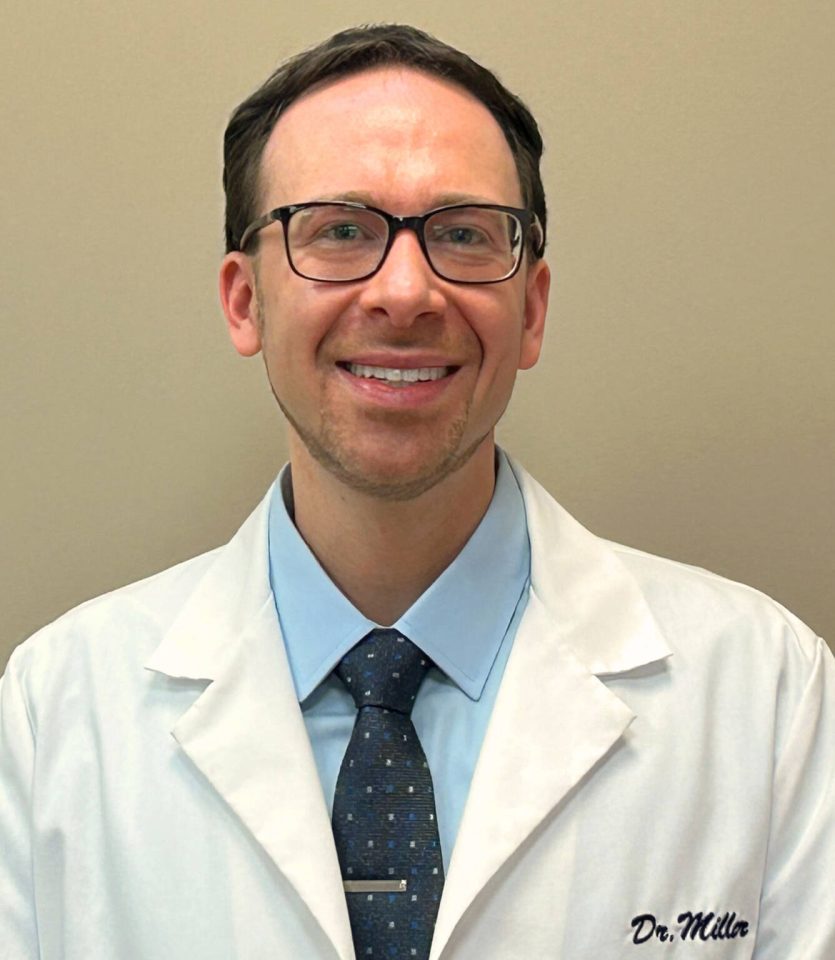 Dr Miller in his lab coat smiling for a head shot.